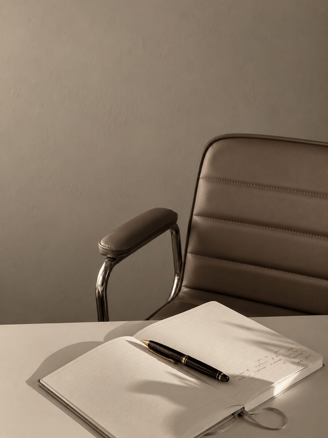 A modern leather executive chair beside a desk with an open notebook